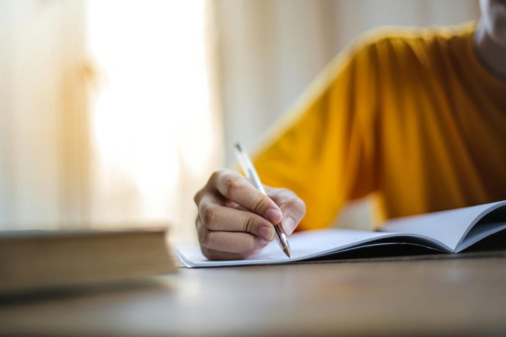Close-up of a person writing in a notebook, symbolizing focus and learning.